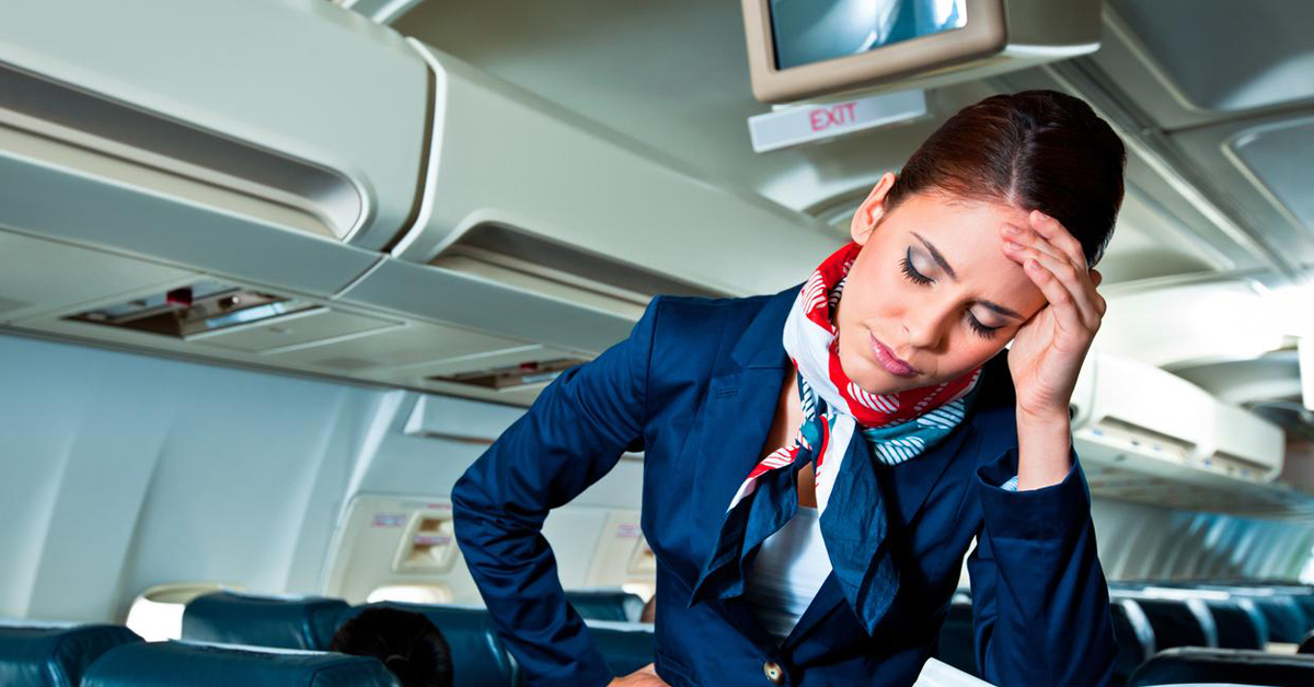 Female Flight Attendant Looking Tired Holding Head On Board Empty Aircraft